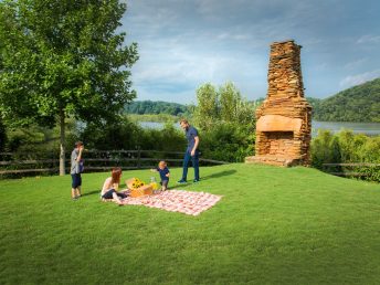A family setting up for a picnic on the grass at Morgan Falls Overlook Park in Sandy Springs, Georgia over by the fireplace.